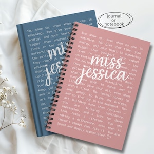 May include: Two spiral-bound notebooks, one blue and one pink, with the text "miss jessica" in cursive. The notebooks have inspirational quotes printed on the pages. The words "journal or notebook" are in a white oval.