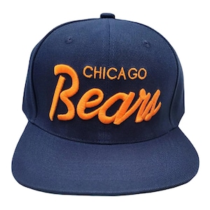 May include: Navy blue baseball cap with the words "CHICAGO Bears" embroidered in orange. The cap has a flat brim and a structured crown. A classic sports accessory.