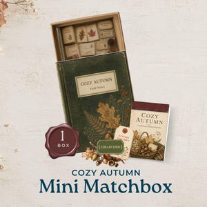 May include: A Cozy Autumn Mini Matchbox set featuring a green box with botanical illustrations, a small book titled Cozy Autumn, a tag labeled Autumn Specimen, and a wax seal graphic with the text 1 BOX. The set includes various paper ephemera.