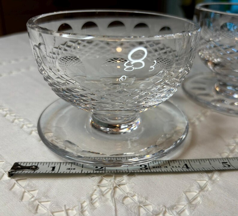 May include: Two clear glass dessert dishes with a pedestal base and a decorative diamond pattern. The dishes are 3 inches in diameter.