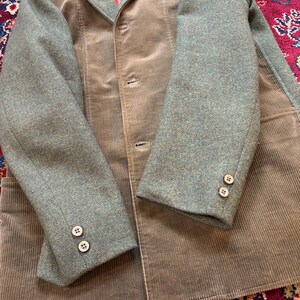 K&ouml;nnte beinhalten: Vintage Cordjacke mit gr&uuml;nen Tweed&auml;rmeln und Kragen. Die Jacke hat eine ged&auml;mpfte olivgr&uuml;ne Farbe mit einem Dreiknopfverschluss und zwei Kn&ouml;pfen an jeder &Auml;rmelmanschette. Das Innenfutter ist lachsrosa.