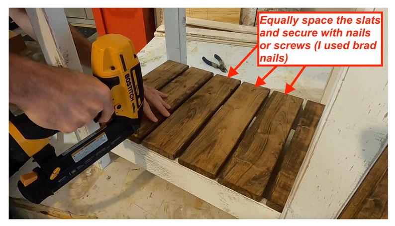 Op de afbeelding: Een persoon gebruikt een spijkerpistool om houten latten aan een wit oppervlak te bevestigen. De tekst in de afbeelding luidt: "Plaats de latten gelijkmatig en bevestig ze met spijkers of schroeven (ik heb brad-spijkers gebruikt)"