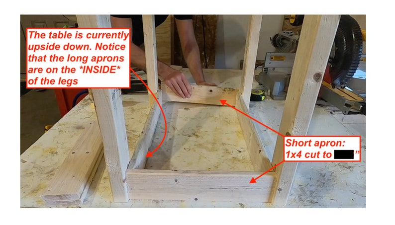 Op de afbeelding: Een houten tafelframe wordt in elkaar gezet. De tafel staat ondersteboven, met de lange schorten aan de binnenkant van de poten. Een korte schort, een 1x4 gezaagd op "..." cm, wordt aan het frame bevestigd.