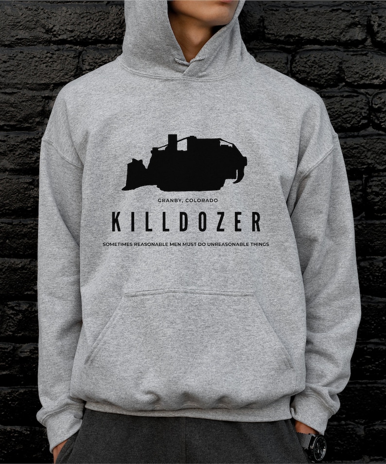 Pode incluir: Camisola de capuz cinzenta com uma silhueta preta de uma bulldozer e o texto "KILLDOZER", "GRANBY, COLORADO" e "SOMETIMES REASONABLE MEN MUST DO UNREASONABLE THINGS".