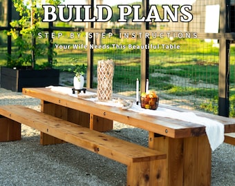 May include: A wooden picnic table with two benches, set up outdoors on a gravel surface. The table is decorated with a white tablecloth, a woven basket of fruit, and candles. The text "BUILD PLANS STEP-BY-STEP INSTRUCTIONS Your Wife Needs This Beautiful Table" is displayed above the table.