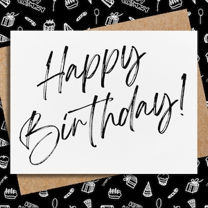 May include: A white card with the text "Happy Birthday!" written in black cursive script. The card is on top of a brown paper background with a black and white pattern of birthday-themed doodles.