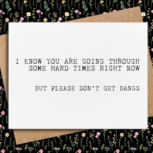 May include: A white greeting card with the text "I KNOW YOU ARE GOING THROUGH SOME HARD TIMES RIGHT NOW BUT PLEASE DON'T GET BANGS" in black, set against a brown envelope. The background features a black floral pattern.