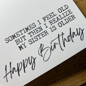 May include: A white card with black text that reads "Sometimes I feel old but then I realize my sister is older. Happy Birthday".