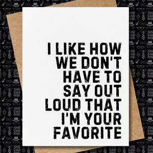 May include: A white greeting card with the text "I LIKE HOW WE DON'T HAVE TO SAY OUT LOUD THAT I'M YOUR FAVORITE" in bold black letters. The card is inside a brown envelope, with a black and white patterned background.