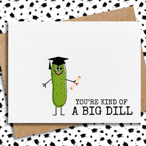 Puede incluir: Una tarjeta de graduaci&oacute;n con un pepinillo verde que lleva un gorro de graduaci&oacute;n y sostiene un diploma. El texto de la tarjeta dice "You're kind of a big dill."