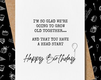 May include: A white card with black text that reads "I'm so glad we're going to grow old together... and that you have a head start. Happy Birthday." A small black and white drawing of a balloon is in the upper right corner.
