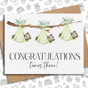 K&ouml;nnte beinhalten: Eine Gru&szlig;karte mit einem Kraftpapierumschlag zeigt eine Aquarellillustration. Drei Teddyb&auml;ren liegen in hellgr&uuml;nen Windeln, die an einem Ast h&auml;ngen. Der Text "CONGRATULATIONS times three!" ist in schwarzer Schrift geschrieben.