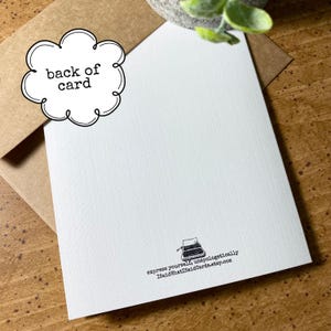 May include: The back of a white card with a black and white illustration of a typewriter. The text "express yourself, unapologetically" and the website "ISaidWhatISaidCards.etsy.com" are printed on the card.