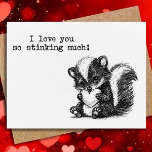 May include: A greeting card with a skunk illustration holding a heart. The card reads "I love you so stinking much!" in black text. The card is on a brown envelope with a red heart background.