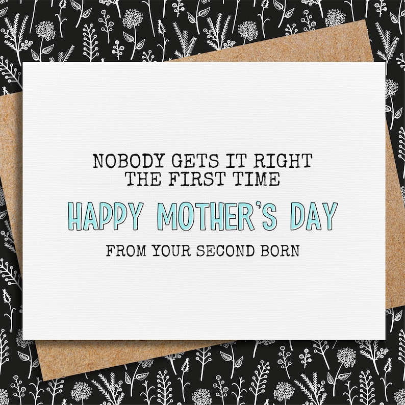 May include: A white Mother's Day card with the text "NOBODY GETS IT RIGHT THE FIRST TIME HAPPY MOTHER'S DAY FROM YOUR SECOND BORN." The card is on a brown envelope, set against a black and white floral background.
