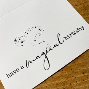 K&ouml;nnte beinhalten: Eine wei&szlig;e Karte mit schwarzem Text, der "have a magical birthday" lautet, mit einer Sternenkonstellation in Form einer Zwei.