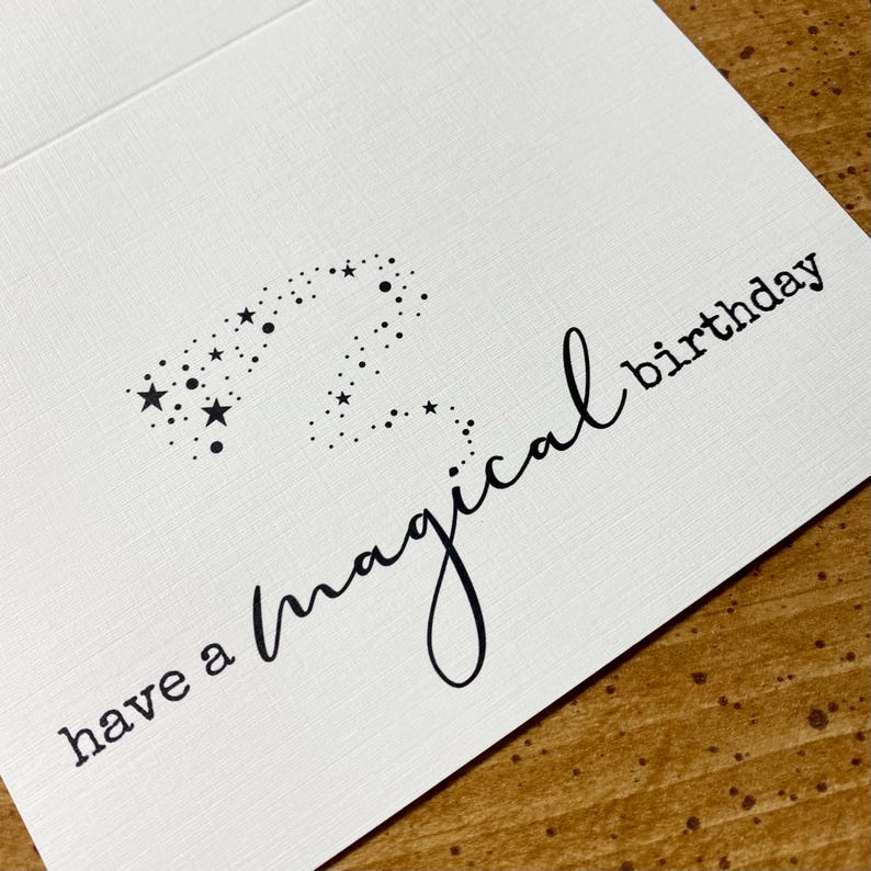 K&ouml;nnte beinhalten: Eine wei&szlig;e Karte mit schwarzem Text, der "have a magical birthday" lautet, mit einer Sternenkonstellation in Form einer Zwei.