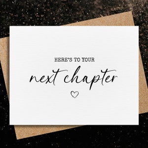 May include: White card with black text that reads "Here's to your next chapter" with a small heart symbol below the text.