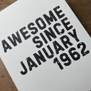 以下が含まれることがあります： 「Awesome since January 1962」という黒い文字が書かれた白いカードです。