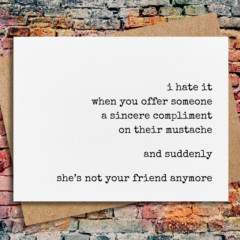 May include: A white greeting card with black typewriter-style text that reads: i hate it when you offer someone a sincere compliment on their mustache and suddenly she's not your friend anymore. The card is placed on a brown envelope.