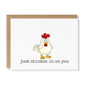 May include: A white greeting card featuring a cartoon chicken with a red comb and wattle, yellow beak, and feet. The chicken has wide eyes and is centered above the black text that reads, "just chicken in on you." The card has a brown envelope.