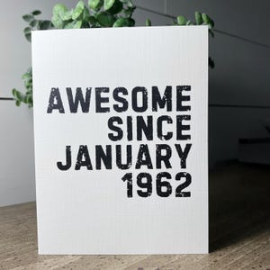 以下が含まれることがあります： 「Awesome Since January 1962」という黒い文字が書かれた白いカードです。