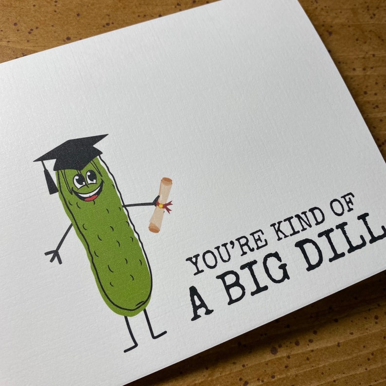 Puede incluir: Un pepinillo verde con un gorro de graduaci&oacute;n y sosteniendo un diploma. El texto "You're kind of a big dill" est&aacute; escrito debajo del pepinillo.