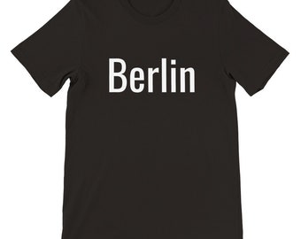 May include: Black t-shirt with the white word "Berlin" printed across the chest. The shirt has short sleeves and a crew neck. The fabric appears to be a soft cotton blend.