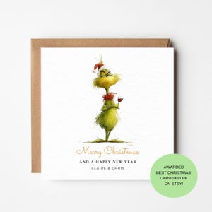 May include: A square white greeting card featuring a watercolour illustration of a green, furry creature wearing a red Santa hat and a red collar, holding a glass of red wine. The text reads Merry Christmas AND A HAPPY NEW YEAR CLAIRE & CHRIS.
