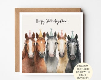 May include: A square greeting card featuring a watercolor illustration of five horses wearing colorful party hats. The text Happy Birthday Alice is printed in black script above the horses. The card is paired with a brown kraft envelope.