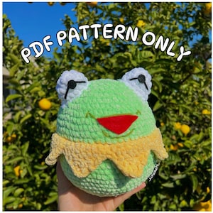 Może przedstawiać: Wzór na szydełku na zieloną zabawkę amigurumi w kształcie żaby z czerwonym pyskiem i żółtym kołnierzykiem. Wzór dostępny jest jako plik PDF do pobrania.  PDF PATTERN ONLY.