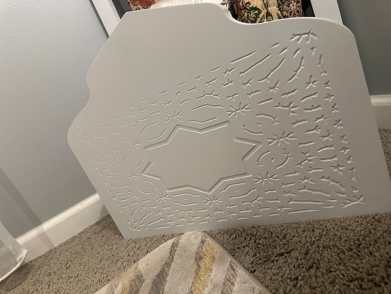 May include: White wooden headboard with a carved starburst design. The headboard has a raised, octagonal center panel.