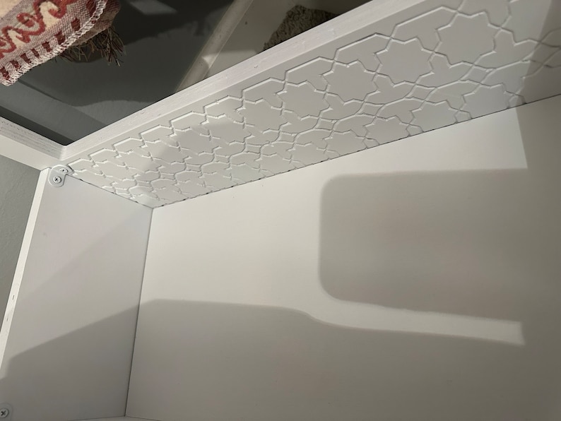 May include: White cabinet with a decorative star pattern on the top edge. The cabinet is empty.