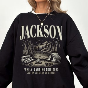 May include: Black sweatshirt with a camping scene and the text "JACKSON FAMILY CAMPING TRIP 2025 CUSTOM LOCATION OR PHRASE".