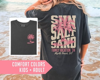 May include: Dark gray t-shirt with a pink palm tree graphic on the front and back. The back of the shirt features the words "SUN SALT SAND FAMILY VACATION '24 Myrtle Beach, SC" in a layered design. The shirt is labeled "COMFORT COLORS KIDS + ADULT".