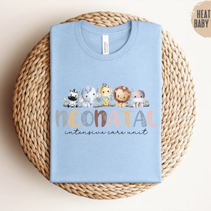 May include: Light blue t-shirt with a graphic of cute animals spelling out "neonatal intensive care unit".