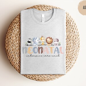 May include: A light gray t-shirt with a design of colorful animals and the text "NEONATAL intensive care unit".