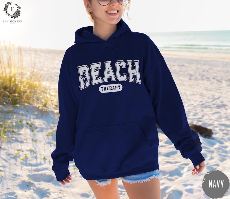 May include: A navy blue hoodie with a white graphic that says "Beach Therapy" with a palm tree design.