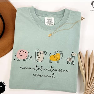May include: A light blue t-shirt with a graphic of an elephant, koala, lion, and zebra. The text "neonatal intensive care unit" is printed below the animals.