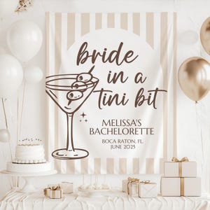 May include: A white and brown striped banner with the text "bride in a tini bit" and a martini glass with olives. The banner also includes the text "Melissa's Bachelorette Boca Raton, FL. June 2025".