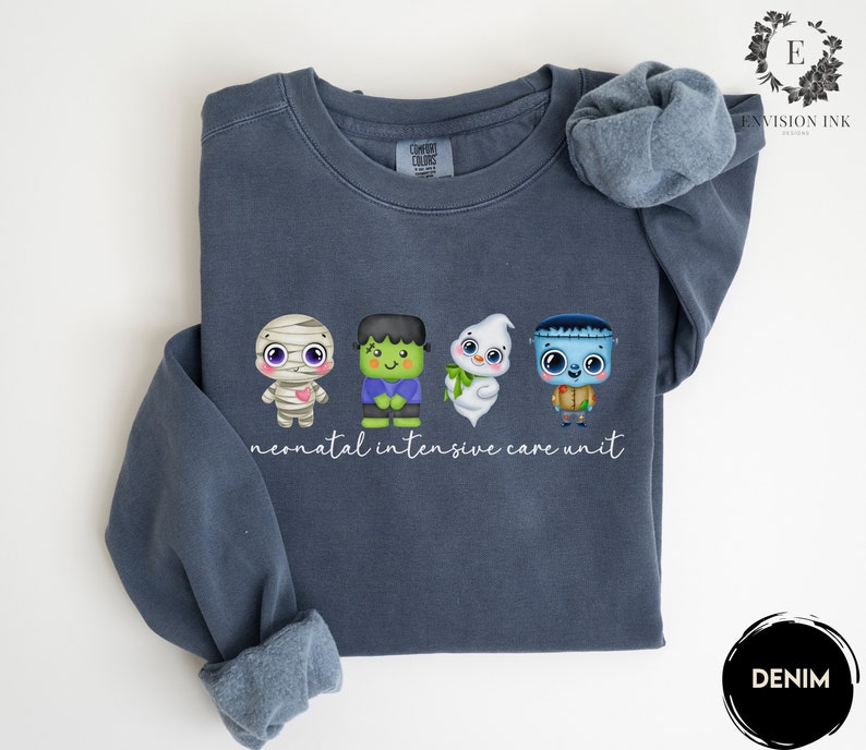 May include: A dark blue sweatshirt with a white graphic of four cartoon monsters and the text "neonatal intensive care unit".