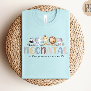 May include: Light blue t-shirt with a graphic of a zebra, elephant, giraffe, lion, and hippopotamus. The text "Neonatal Intensive Care Unit" is printed below the animals.