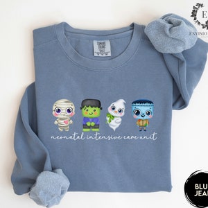 May include: A blue sweatshirt featuring a graphic of four cute Halloween characters and the text "neonatal intensive care unit".