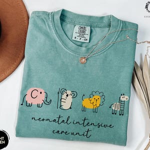 May include: Light green t-shirt with a graphic of an elephant, koala, lion, and zebra. The text "neonatal intensive care unit" is printed below the graphic.