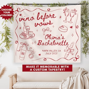 May include: White tapestry with red text and illustrations. The text reads "vino before vows Olivia's Bachelorette Napa Valley, CA July 2025". The illustrations include wine bottles, glasses, grapes, a baguette, and a ring.