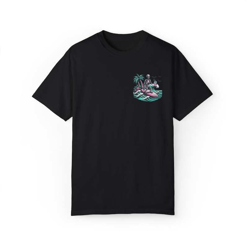 K&ouml;nnte beinhalten: Schwarzes T-Shirt mit einem Motiv eines Skeletts, das auf einem rosafarbenen Surfbrett mit einer Palme und einem Cocktail in der Hand surft.