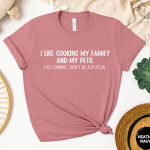 May include: A heather mauve t-shirt with white text that reads "I like cooking my family and my pets. Use commas. Don't be a psycho."