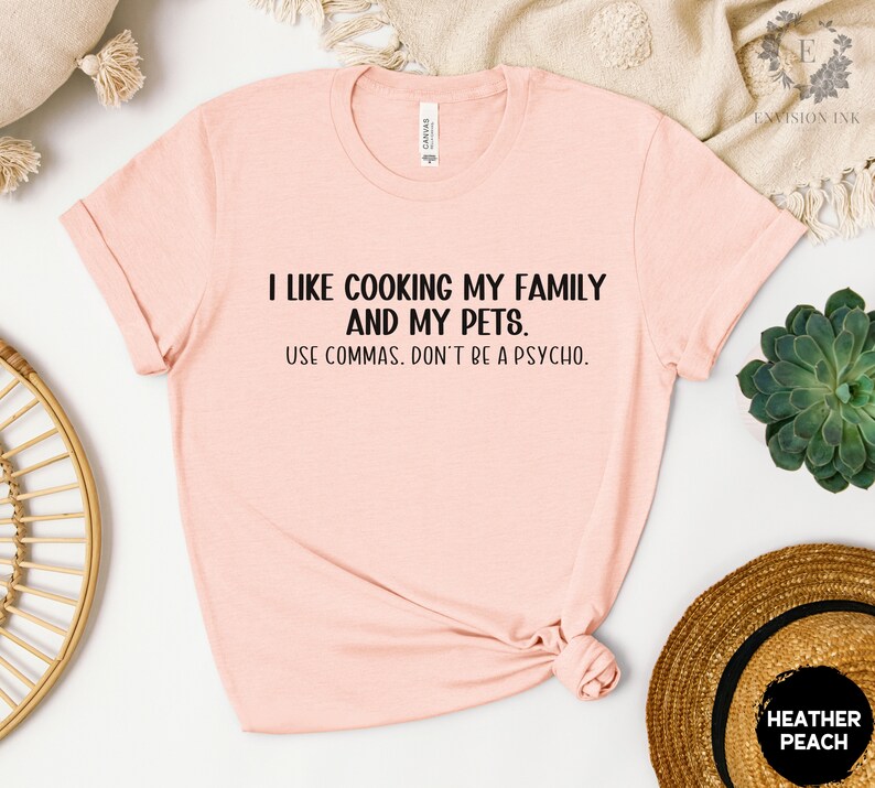 May include: A pink t-shirt with the text "I like cooking my family and my pets. Use commas. Don't be a psycho." printed in black.