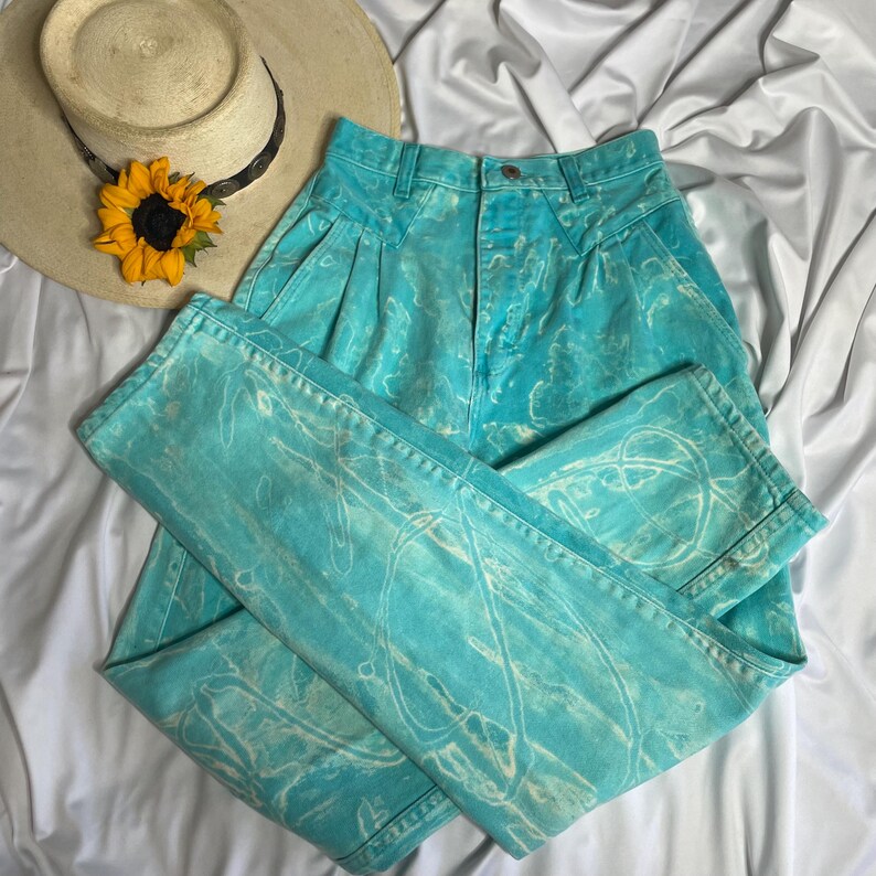 Op de afbeelding: Een high-waisted jeans in lichtblauw met een wit tie-dye patroon. De jeans heeft een relaxte pasvorm en een rechte pijp.