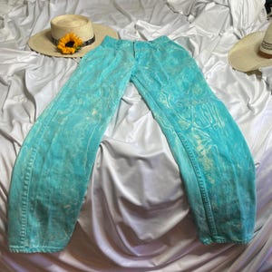 Op de afbeelding: Een lichtblauwe spijkerbroek met een tie-dye patroon. De broek heeft een ontspannen pasvorm en een rechte pijp.